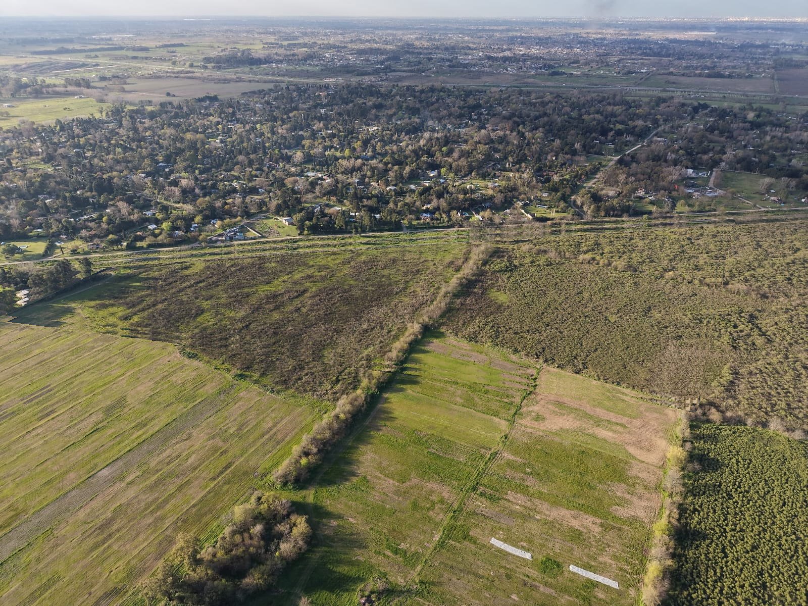 Foto de dron del predio de Sol de Junio en su estado actual: campo abierto junto a la zona de quintas de 20 de Junio y las vías del Belgrano Sur